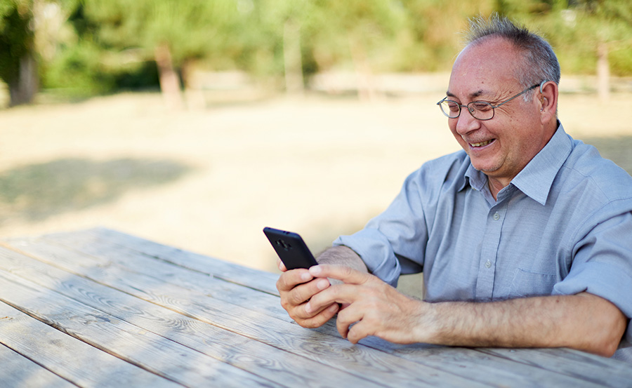 Man smiling and using phone outside