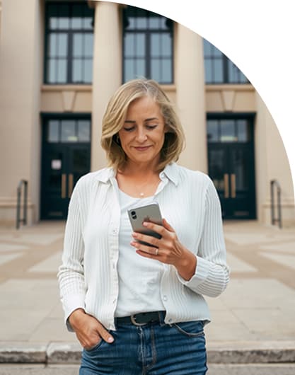 A woman stands in front of a government building while on her mobile phone.