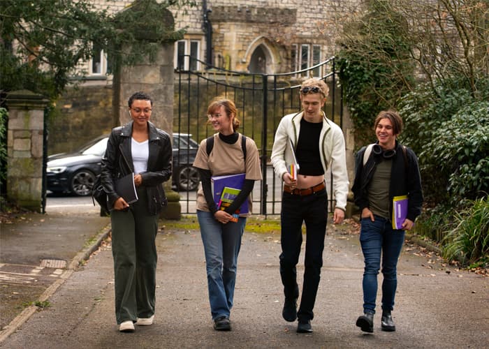 A group of students carrying books and chatting as they walk to class.