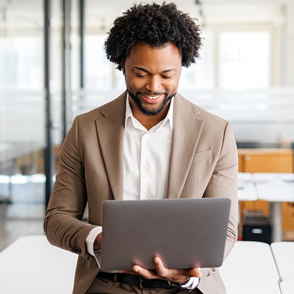Man holding a laptop in one hand and typing with the other