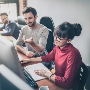 A man and a woman talk about what is on their computer screen