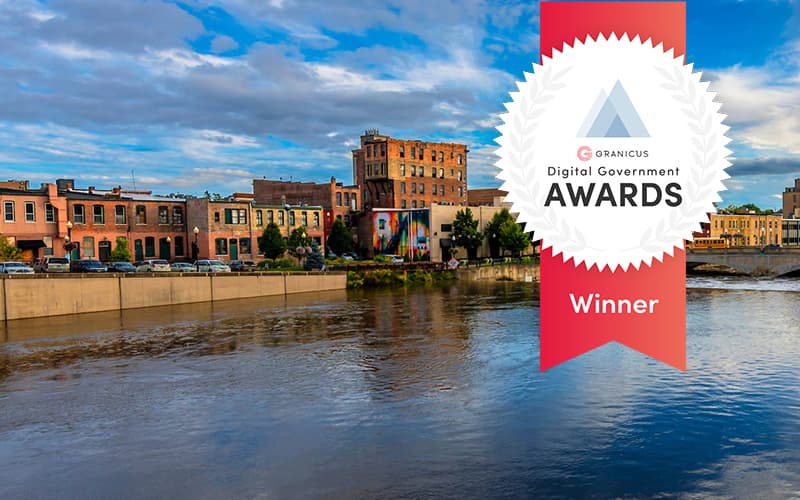 Riverfront view of downtown Aurora, Illinois, alongside a Granicus Digital Government Awards winner badge recognizing the city’s work to improve resident engagement.