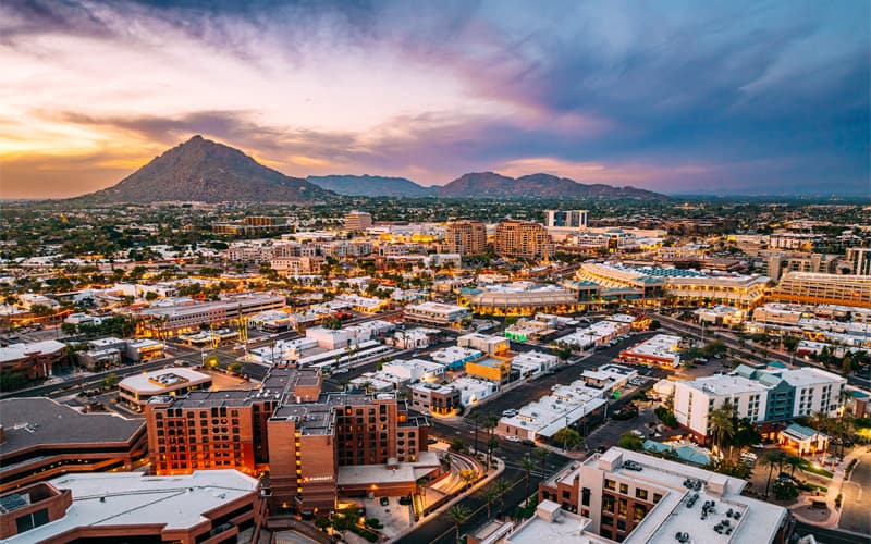 Aerial view of Paradise Valley at dusk, showing low-rise buildings and residential areas set against desert mountains, illustrating a well-managed community landscape.