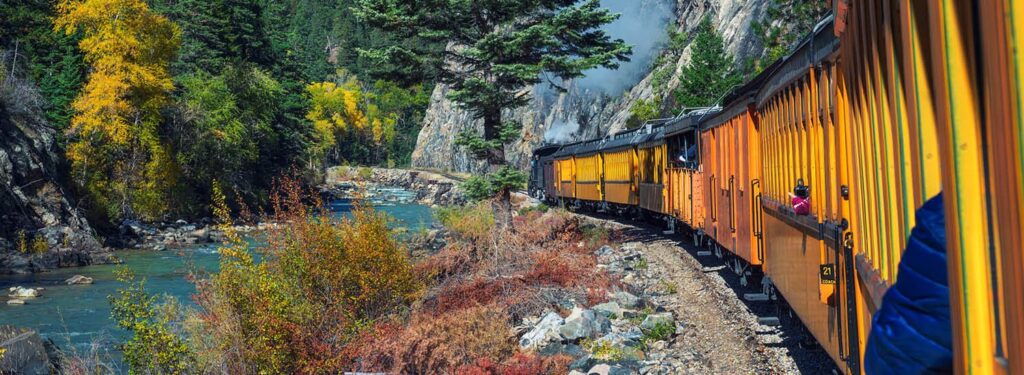 Historic, bright-colored train winding through the Colorado wilderness on a bright, spring day