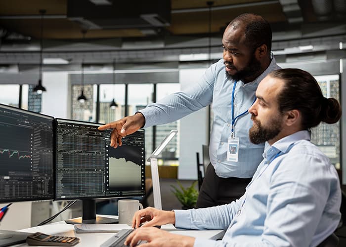 Two colleagues looking at charts and data on a computer screen