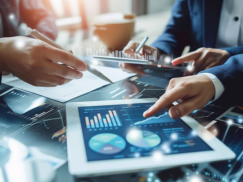 Three federal employees collaborating while analyzing data analytics on a computer screen, highlighting federal agencies' commitment to enhancing customer experience (CX) in 2025 through data, AI, and digital engagement.