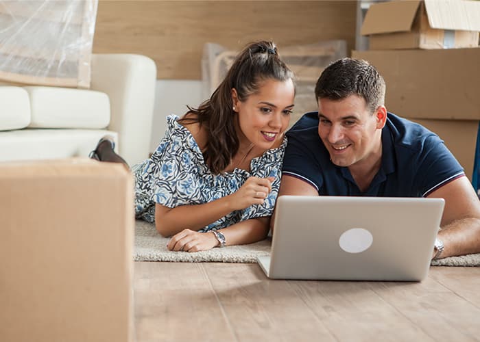 Young adults using their laptop in the new flat for new furniture