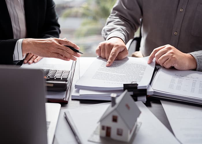 Businessman and client discussing a real estate investment and home sales contract documents.