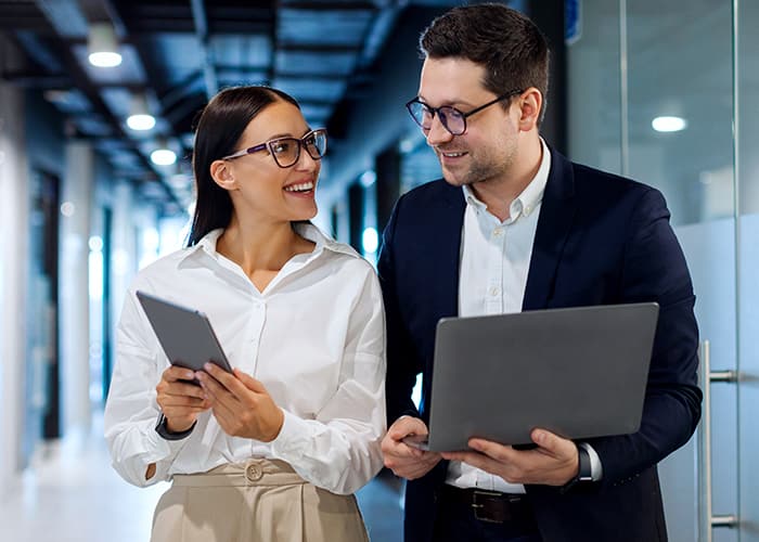 Business professionals collaborating in modern office environment, using tablet and laptop together