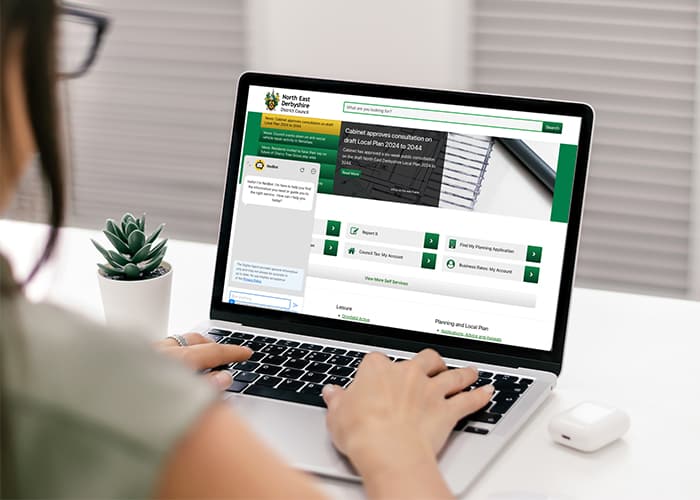 Woman using a laptop to navigate a website with an AI chatbot assistant.