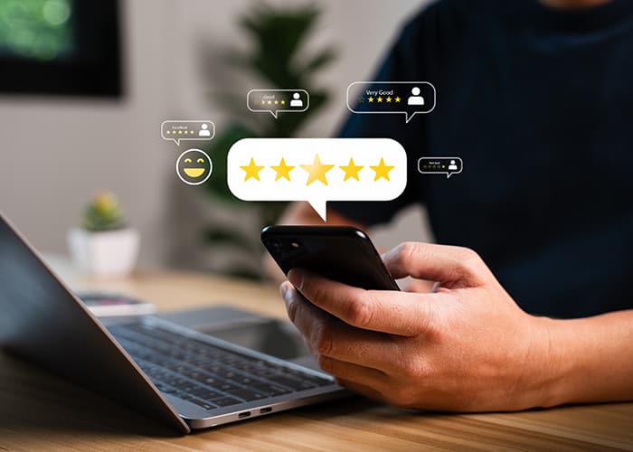 Resident providing feedback on a government digital service via smartphone, with laptop on a wooden table, representing satisfaction and user experience.