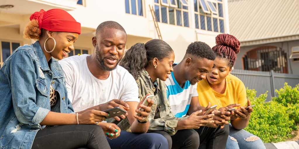 A group of community members engaging in conversation while showing each other their phone screens.