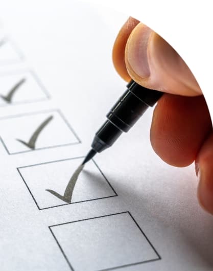 A close up shot of a person's hand holding a marker and going through a checklist on paper.