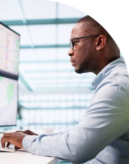 Person working on dual monitors displaying data and charts in a modern office, representing AI-driven solutions for local government service delivery.