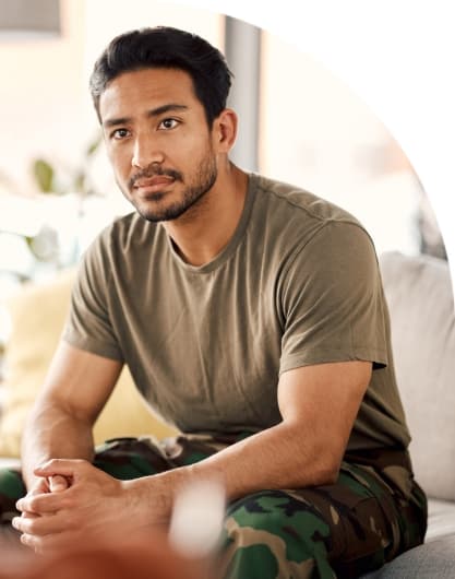 Veteran seated on a couch in casual attire, symbolizing strength and reflection in a supportive environment.