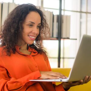 Mujer puertorriqueña trabajando con una computadora portátil en el sofá