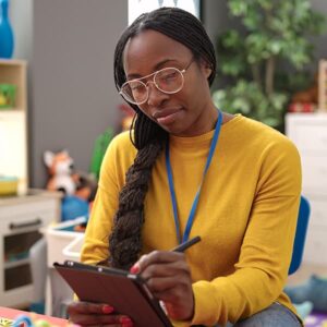 Black woman working on a tablet, symbolizing efforts to drive operational efficiency through technology.