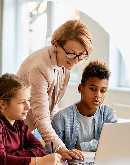 Teacher helping students with technology in classroom