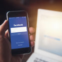End of an Era – New Facebook Algorithm Marks Social Media’s Decline as Engagement Tool image Facebook App on iPhone with computer laptop background closeup male hand hold social network on smart device concept.