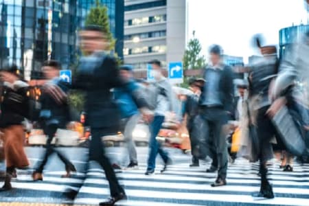 Professionals in suits walking on a busy crosswalk in a city