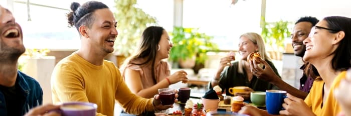 A group of friends sitting outside having a conversation and smiling.