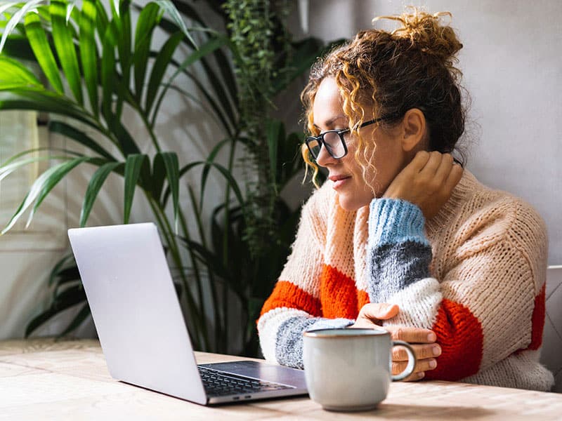 Woman sitting in front of her laptop thinking of solutions to challenges.