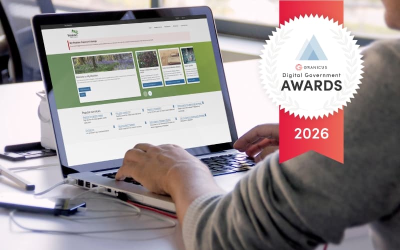 Person using a laptop displaying a local government self-service portal beside a 2026 Granicus Digital Government Awards badge.