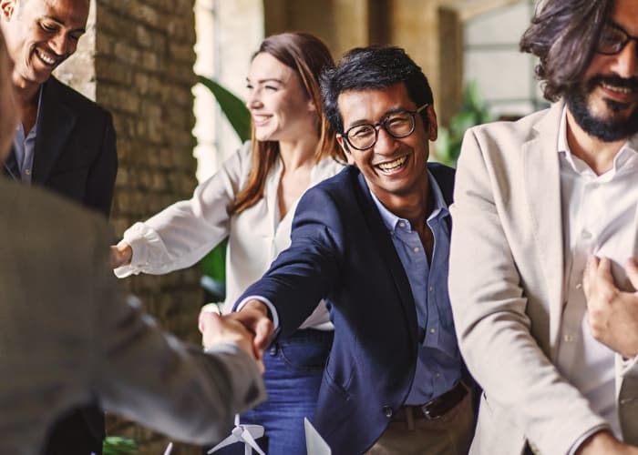 A group of business people smiling and shaking hands.