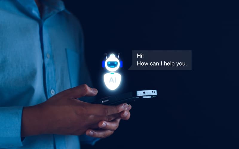 Person holding smartphone with holographic AI chatbot saying 'Hi! How can I help you.'