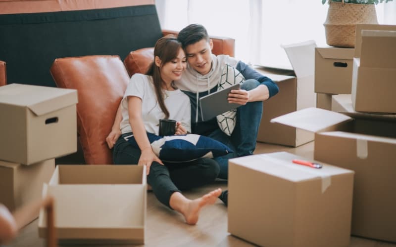 Residents in a new home reviewing information on a tablet among moving boxes, reflecting tenant experience and feedback in a residential setting.