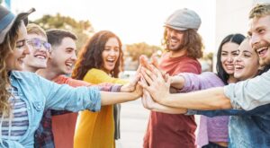 A group of friends smile as they all high-five one another at the same time.