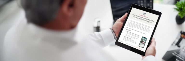 A man holding a tablet while reviewing a flash flood communication strategy toolkit.