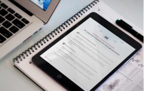 Tablet displaying 'An essential checklist for local government' next to a notebook, laptop, and pen.