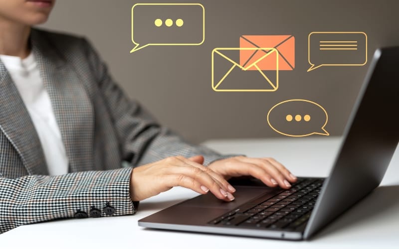 A person in a suite types on a laptop with communication and notification icons overlaid.