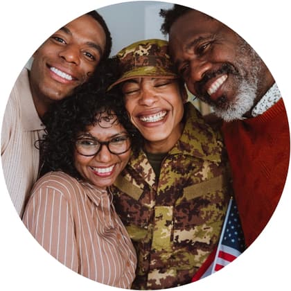 Group of people standing together with one person wearing a camouflage uniform and holding an American flag.