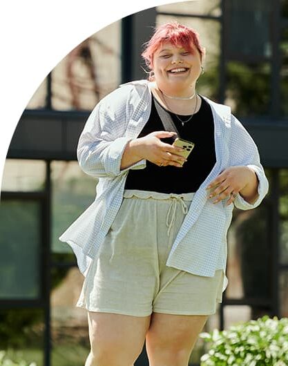 Young adult woman smiling while walking with her phone as she communicates with easily and painlessly with her local council.