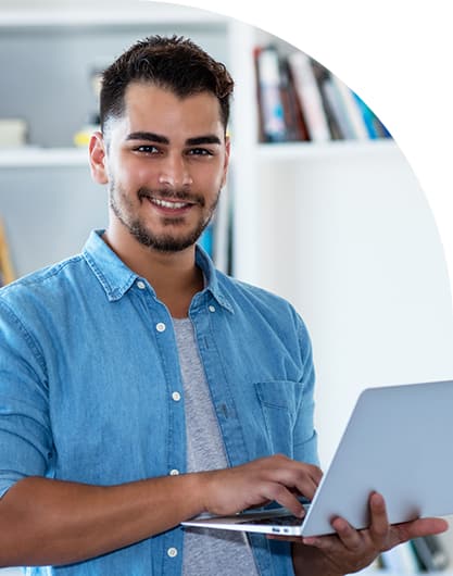 Hombre sonriendo a la cámara, sosteniendo una laptop con sus manos